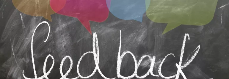 La palabra 'feedback' escrita en un pizarrón con bocadillos de colores.