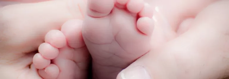 Pies pequeños de bebé sostenidos por manos adultas.