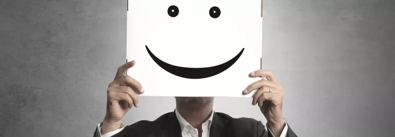 Persona sosteniendo un cartel con una cara sonriente.