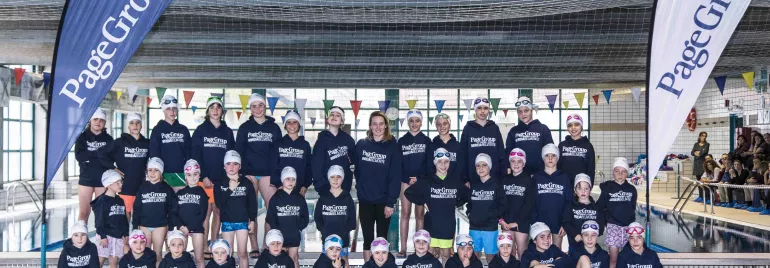 Grupo de personas en una piscina cubierta con camisetas a juego.