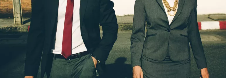 Dos personas caminando con trajes formales.