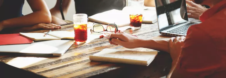 Personas reunidas en una mesa tomando notas con bebidas frías.
