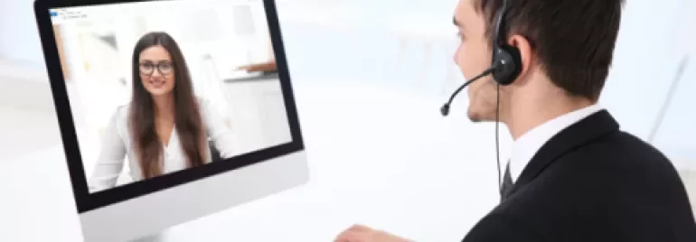 Persona en videollamada con auriculares, trabajando frente a un ordenador.