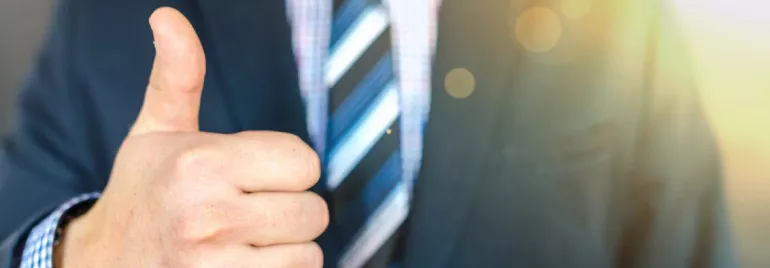 Persona en traje dando señal de aprobación con el pulgar.