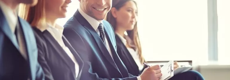 Grupo de personas en trajes formales sonriendo en una reunión.