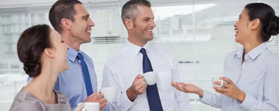 Grupo de personas conversando y bebiendo café en una oficina.