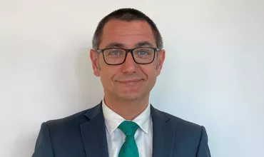 Persona con gafas y traje azul sonriendo