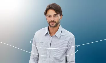 Persona sonriendo con camisa a rayas en fondo azul.