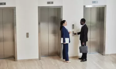 Two people talking in front of the elevator