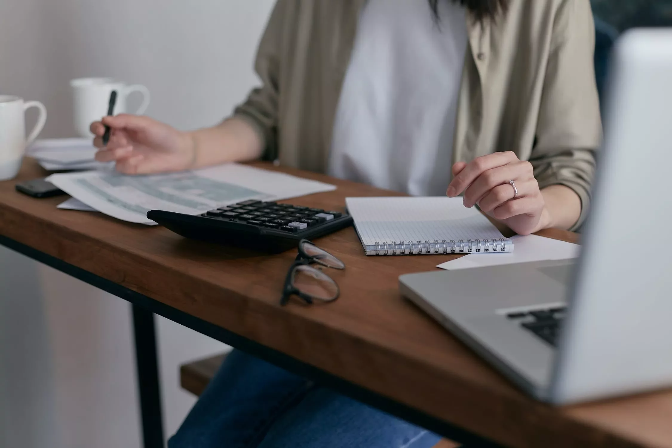 Persona usando calculadora y tomando notas en un escritorio.