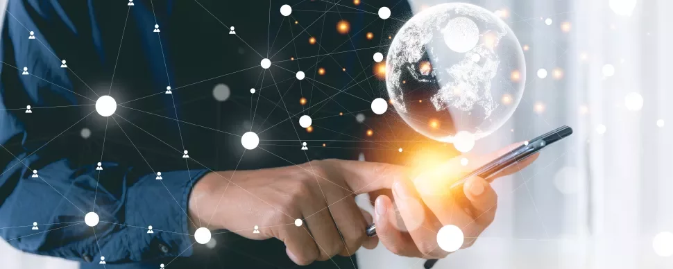 Persona usando un teléfono móvil con un holograma del mundo y conexiones de red.
