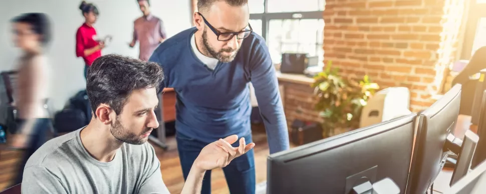 Dos personas trabajando en un ordenador en una oficina moderna.