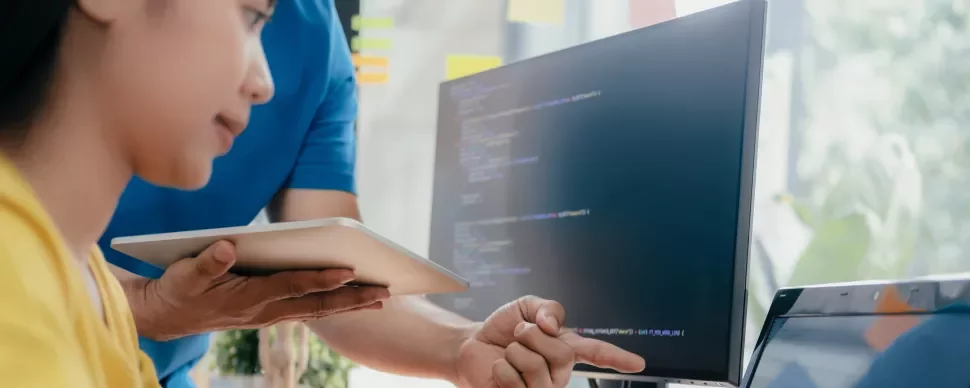 Personas colaborando frente a una pantalla con código.