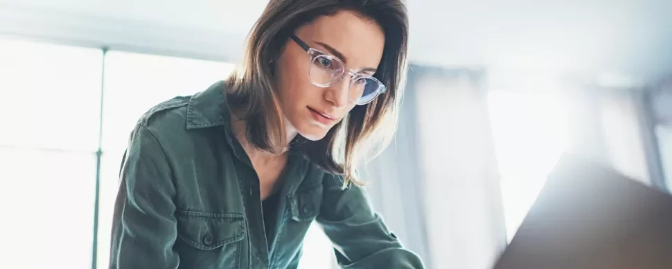 Persona con gafas trabaja concentrada frente a una computadora.