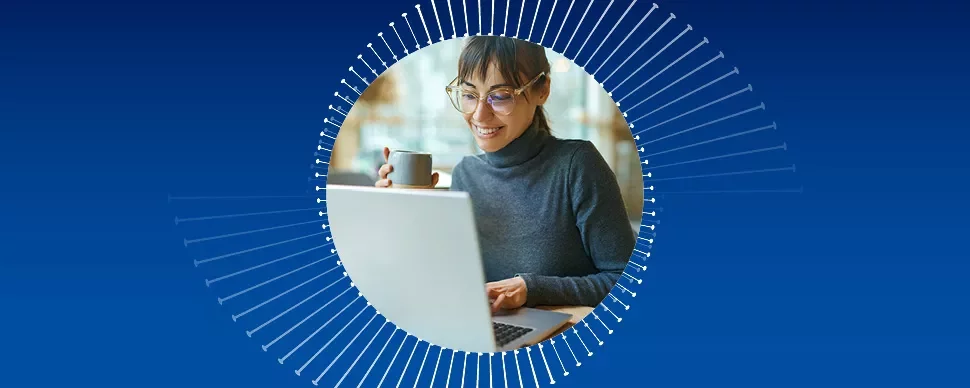 Persona trabajando en una computadora portátil con una taza en la mano.
