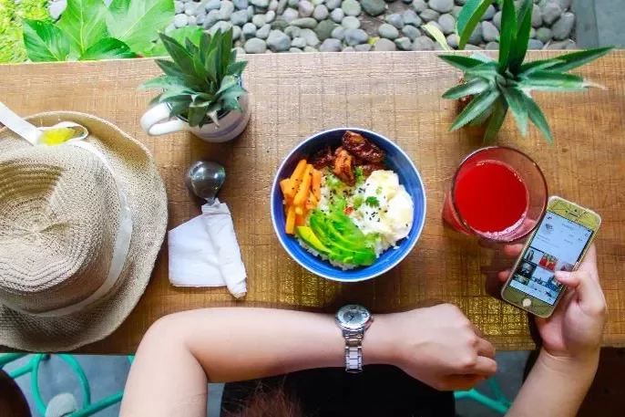 Vista cenital de un plato con verduras junto a un sombrero y bebida.
