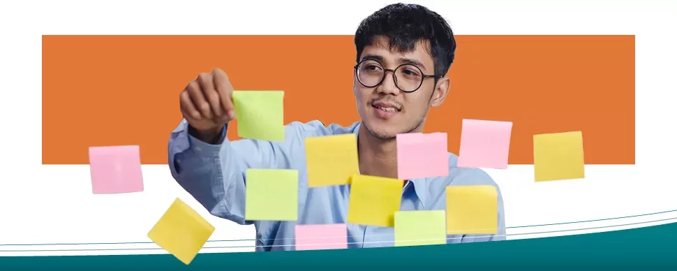 Persona organizando notas adhesivas en una pared.