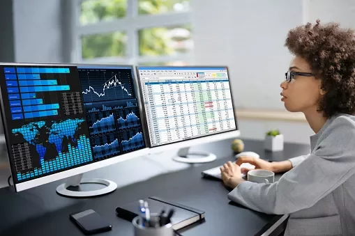 Persona trabajando en una computadora con gráficos de datos y hojas de cálculo.