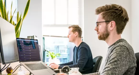 Personas trabajando en ordenadores en una oficina moderna.