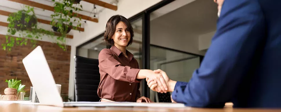 Mujer dándole la mano de forma profesional a un hombre sentados como en entrevista