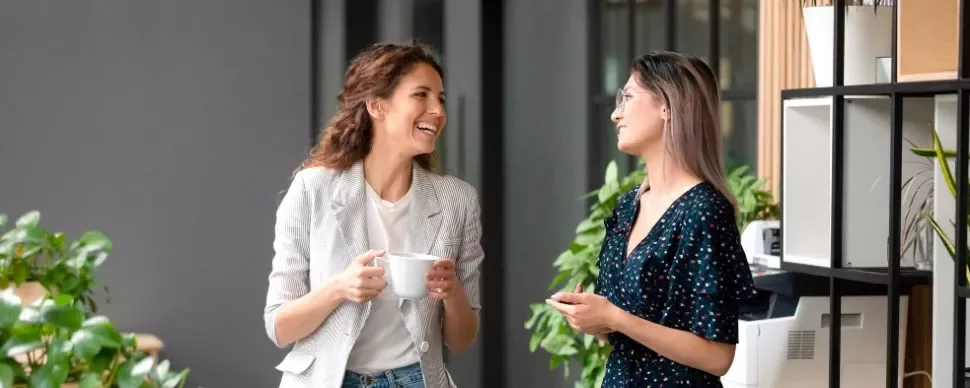 dos mujeres hablando y sonriendo con mucha inteligencia emocional
