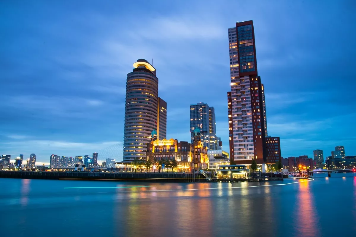 Vista nocturna de una ciudad moderna junto al río, con edificios iluminados.