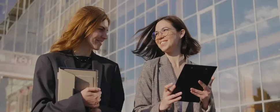 dos chicas saliendo de la oficina a una reunión con una tablet en las manos