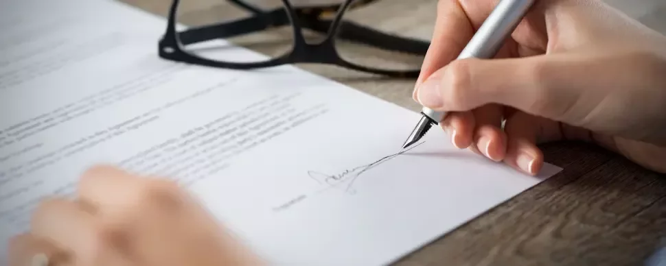 mano firmando un contrato con una pluma