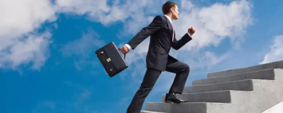 Persona subiendo escaleras al aire libre con un maletín.
