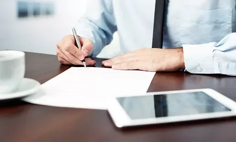 Persona firmando un documento en una oficina.