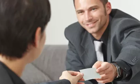 Persona entregando una tarjeta a otra persona en una reunión.