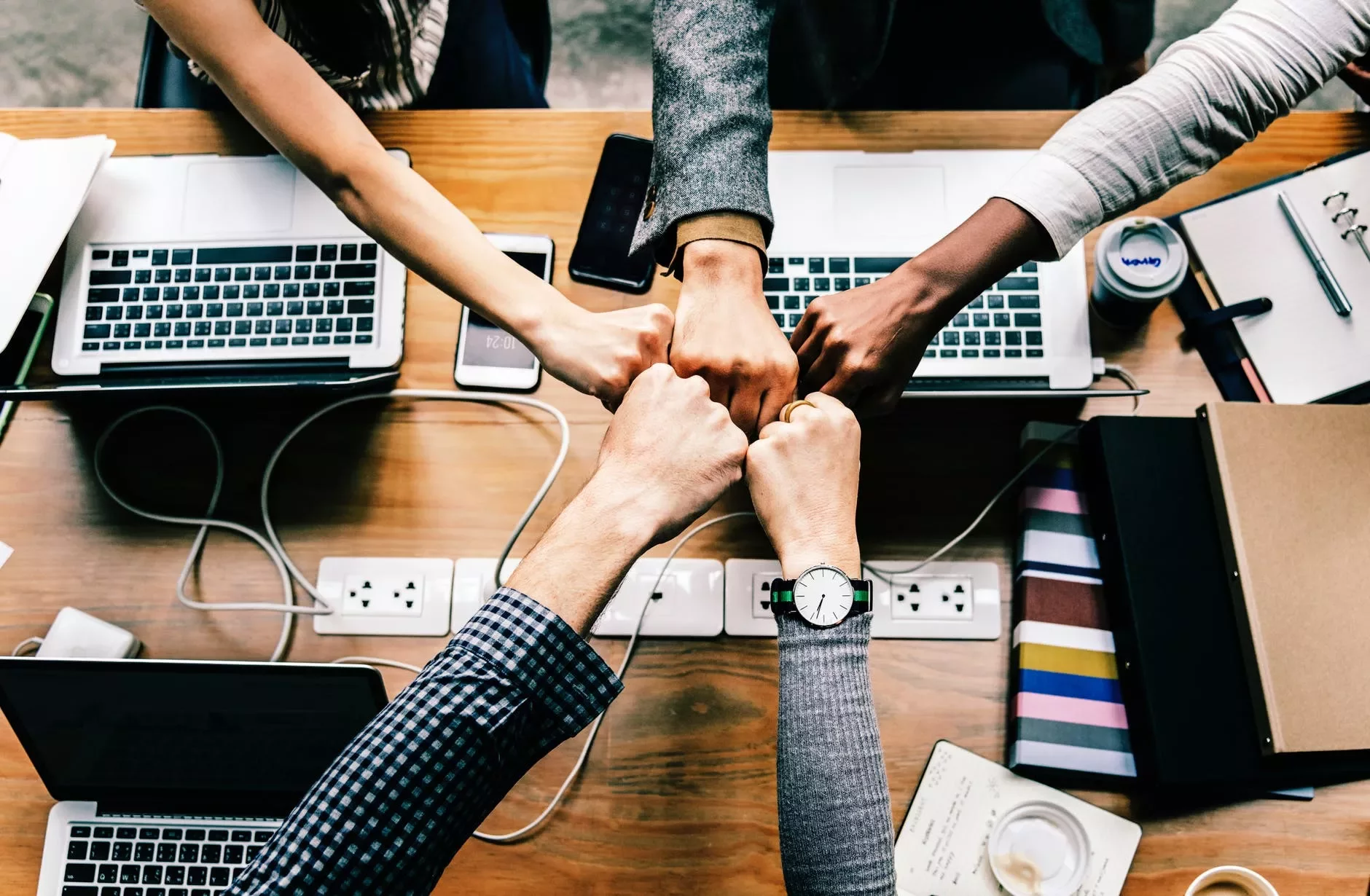 Cinco manos unidas sobre una mesa de oficina.