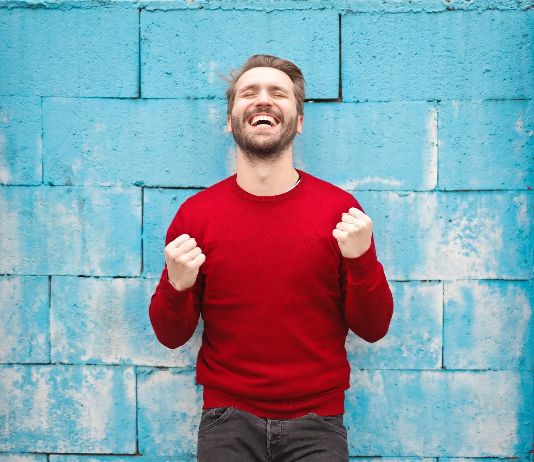 Persona sonriente vestida de rojo frente a un muro azul.