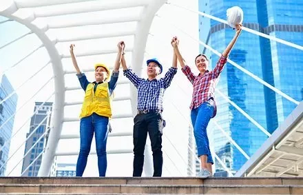 Trabajadores de la construcción levantan las manos juntos en una estructura moderna de la ciudad.