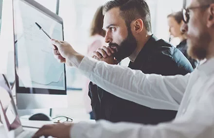 Personas trabajando en una computadora analizando datos.