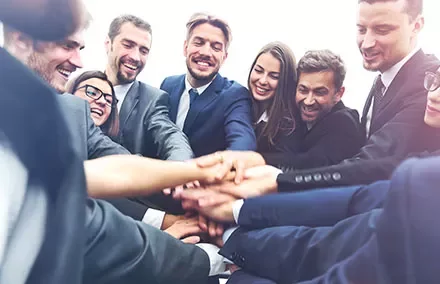 Grupo de personas uniendo sus manos en señal de trabajo en equipo.