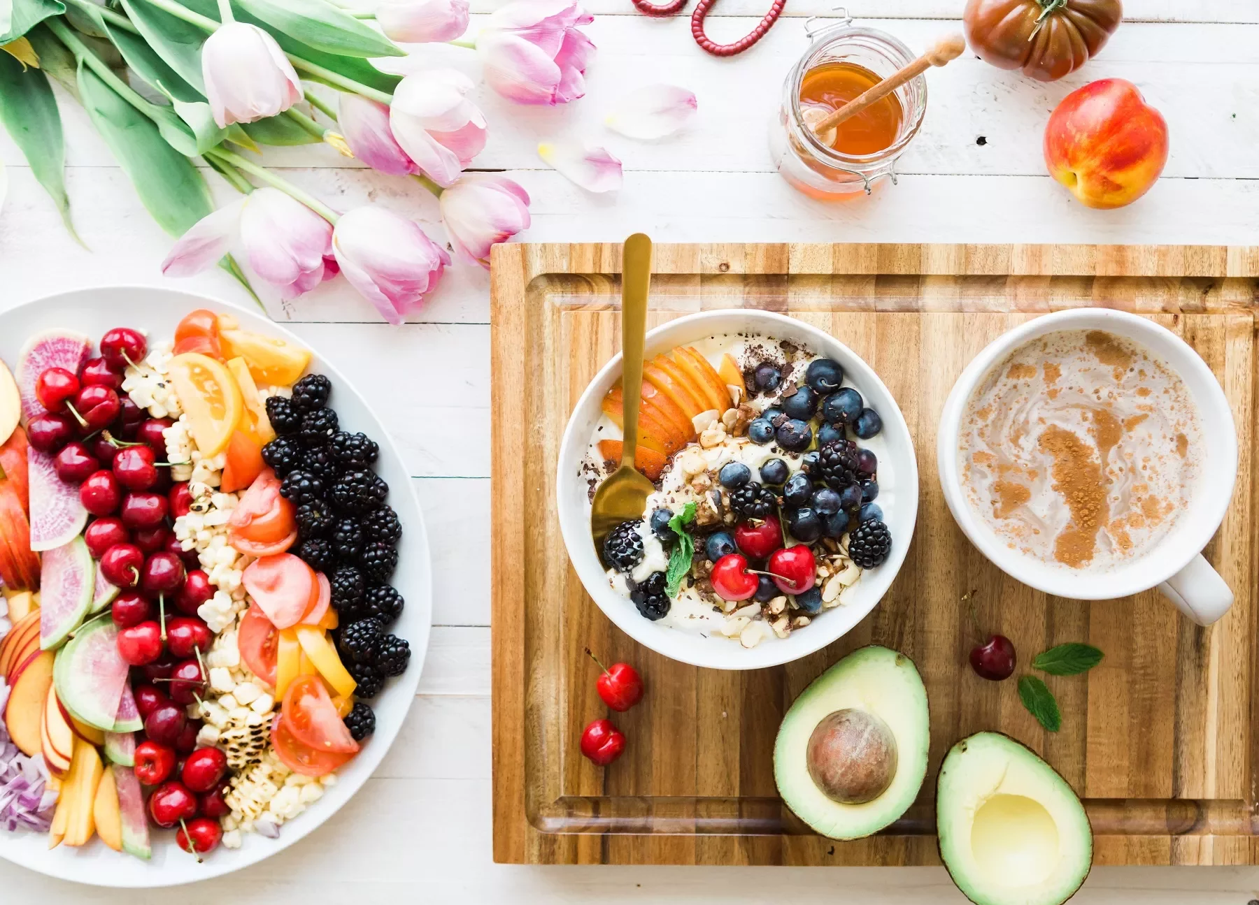 Mesa con frutas, yogurt, café y flores.