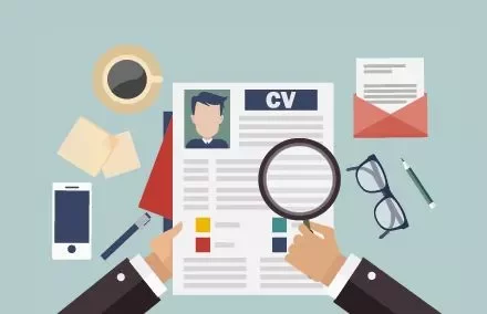 Manos sosteniendo un CV con lupa, taza de café y gafas.