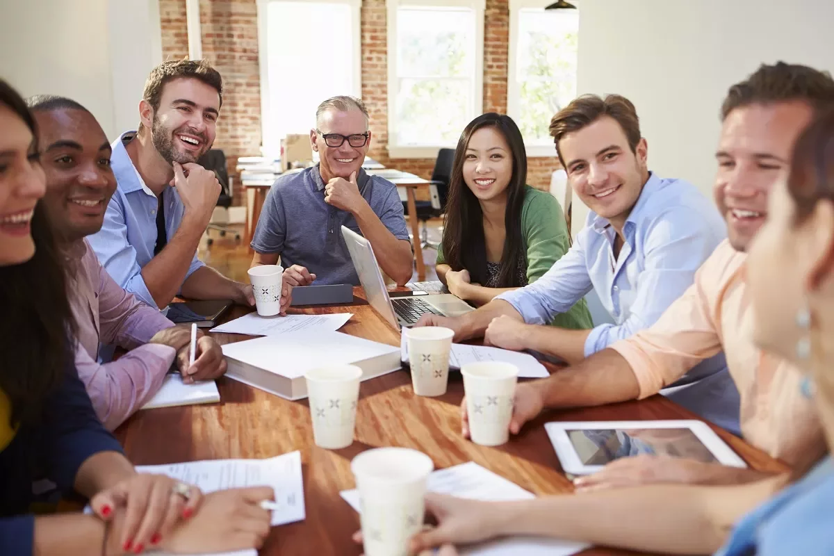 Grupo de personas en reunión de trabajo en una oficina luminosa.