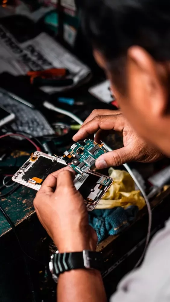 Manos arreglando las piezas internas de un smartphone.
