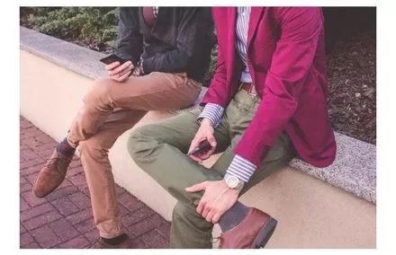 Dos personas sentadas en un banco usando teléfonos móviles.
