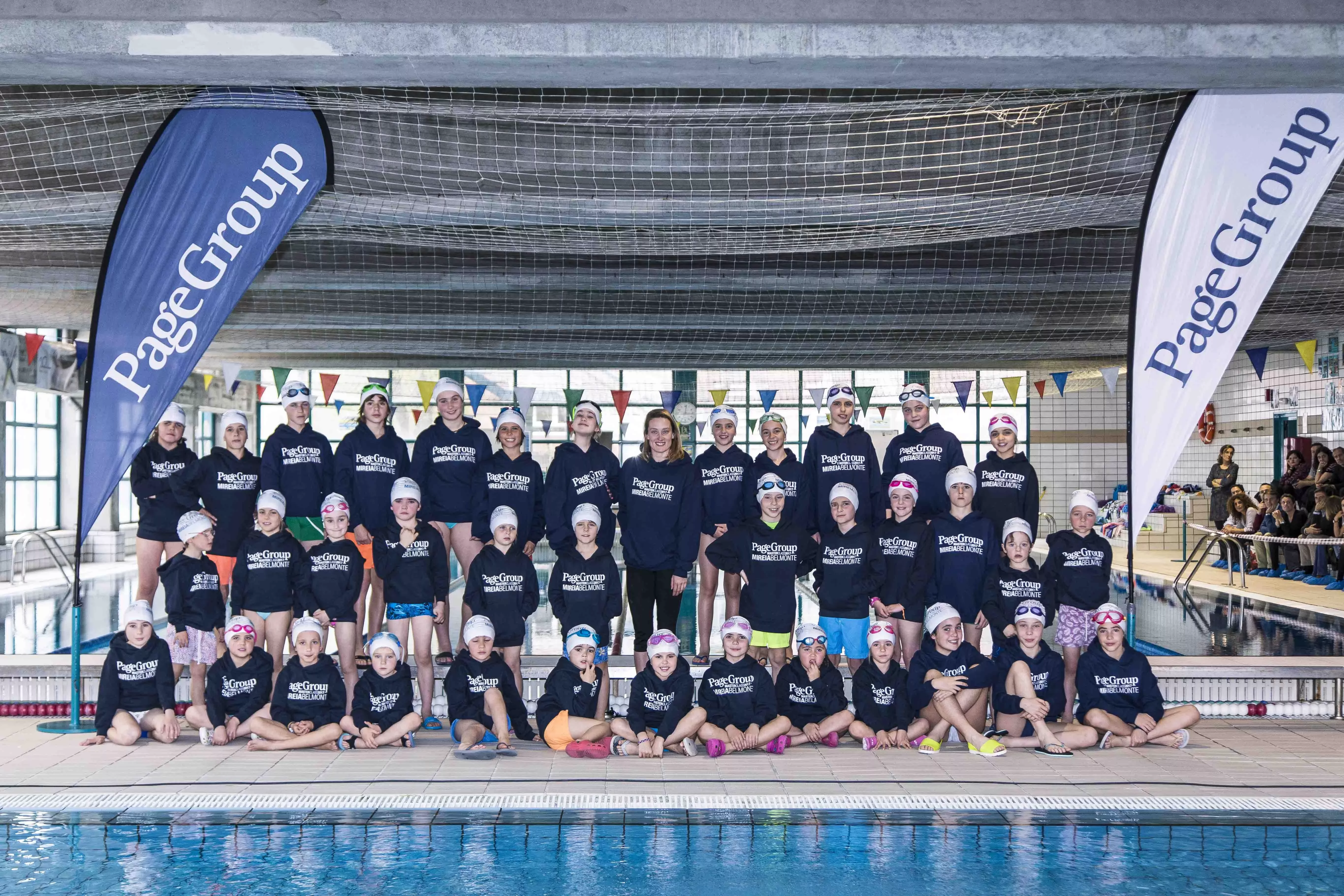 Grupo de personas en una piscina cubierta con camisetas a juego.