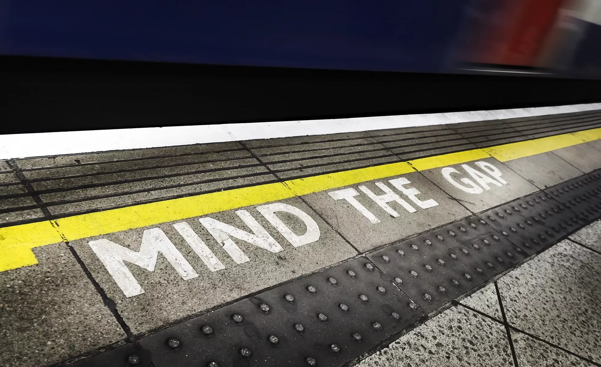 Texto en el suelo de una estación de metro: 'Mind the Gap'