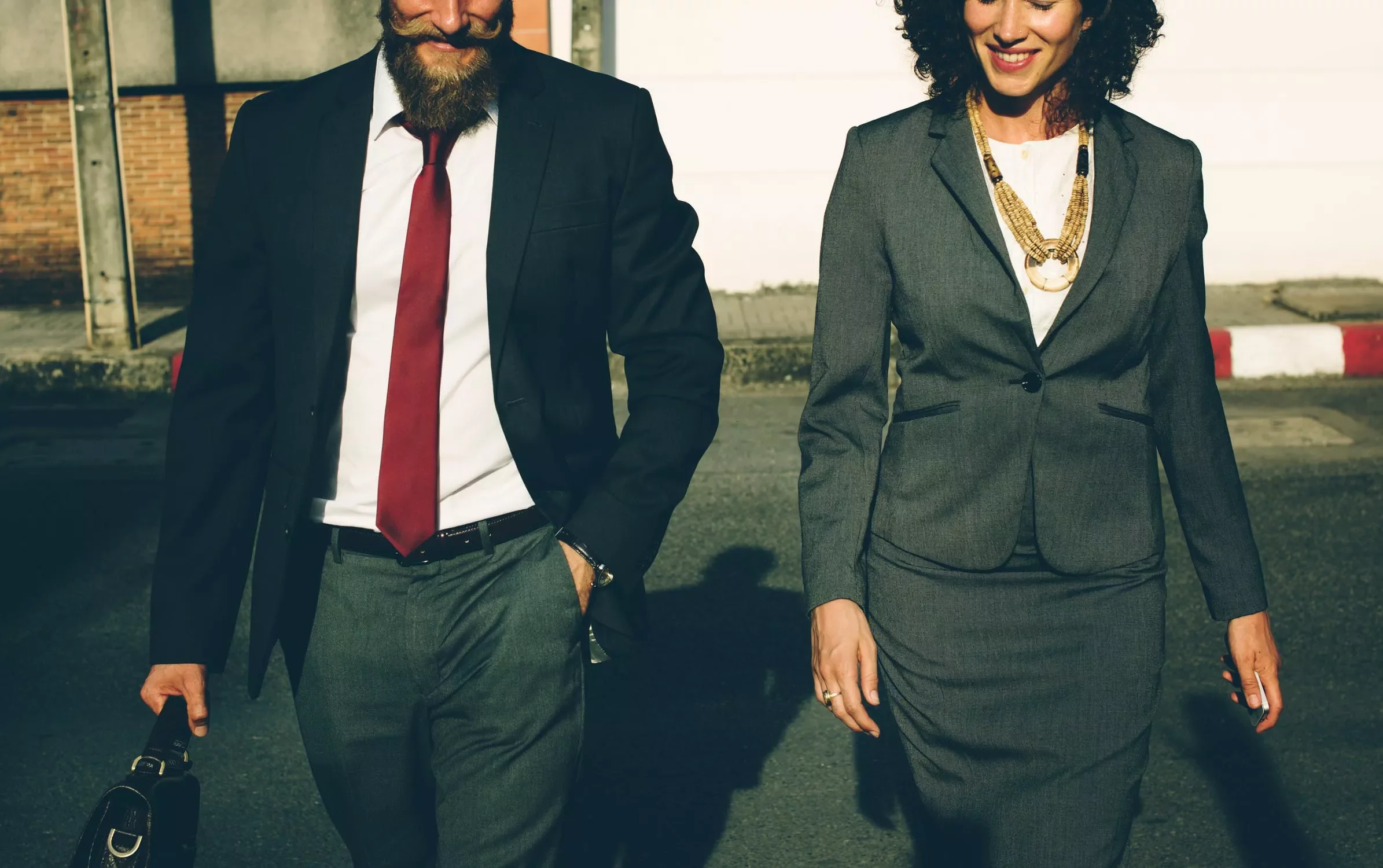 Dos personas caminando con trajes formales.