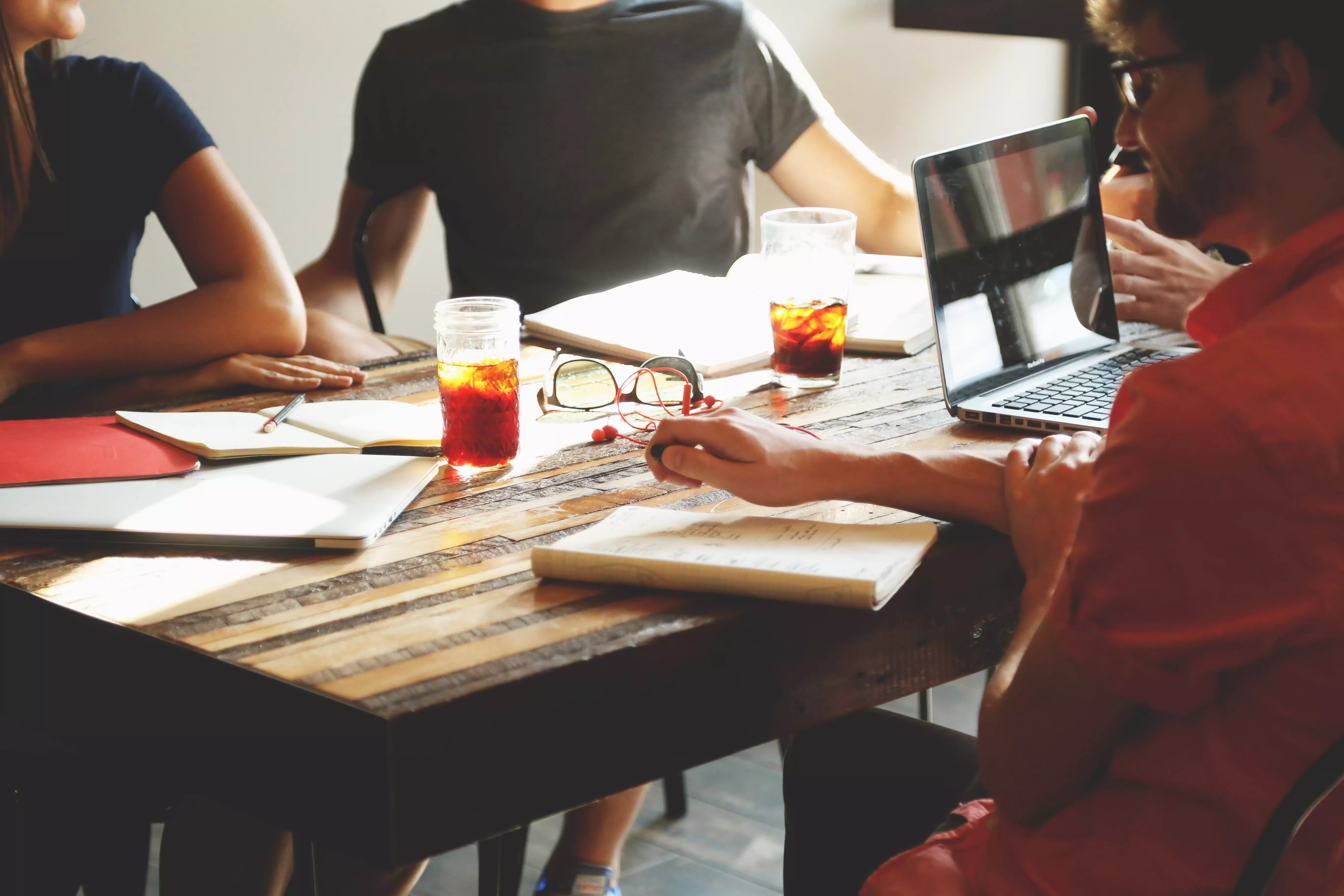 Personas reunidas en una mesa tomando notas con bebidas frías.