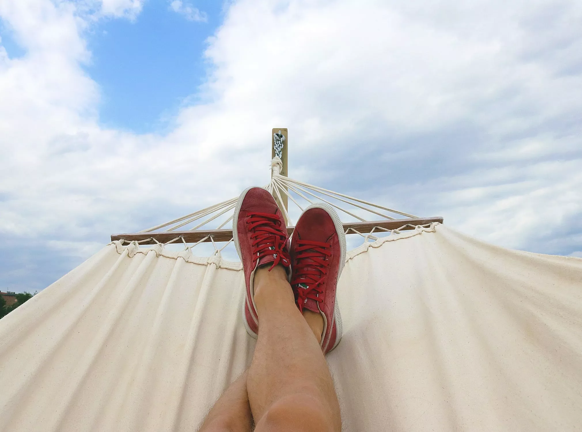 Relajación en una hamaca con zapatos rojos bajo el cielo azul.