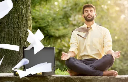 Persona meditando al aire libre con papeles volando.